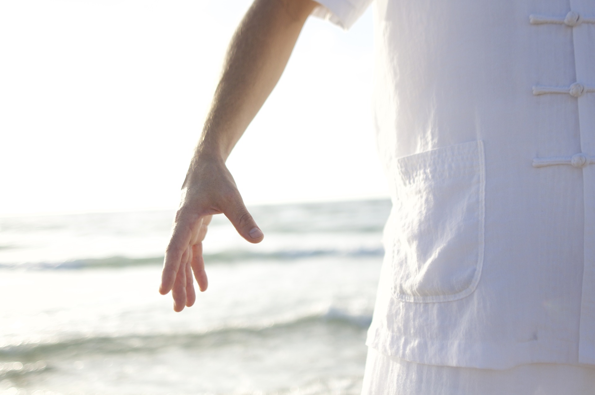 un homme devant la mer avec un bras levé 
